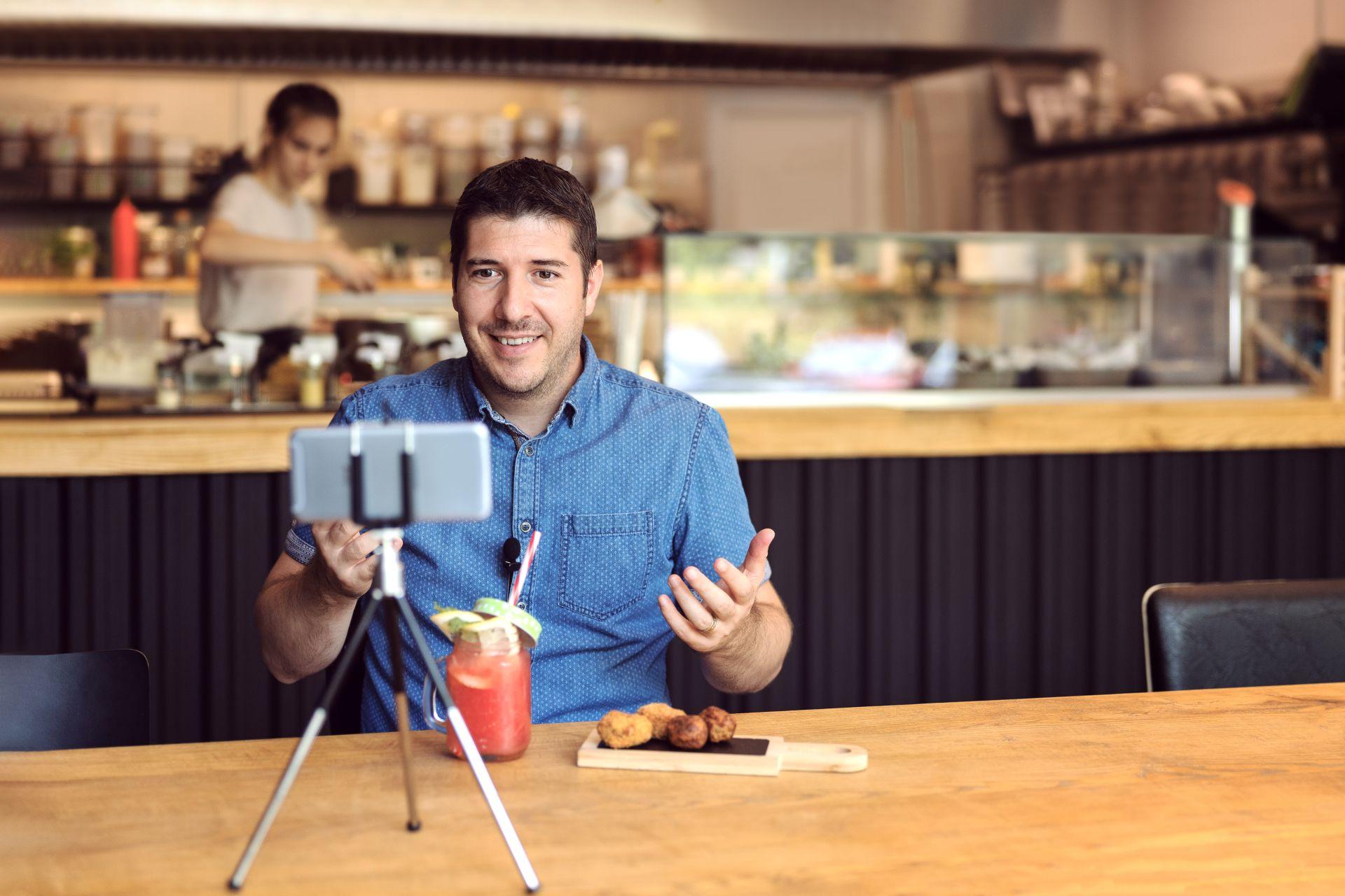Man creating a food video in a restaurant, representing the modern creator economy and onlyfans job application.